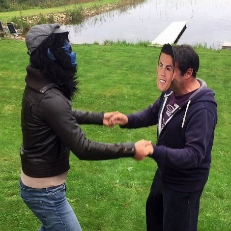 Der blaue Affe Kalle tanzt im Garten Hand in Hand mit einem Mann, der eine Maske vom Fußballer Ronaldo trägt.